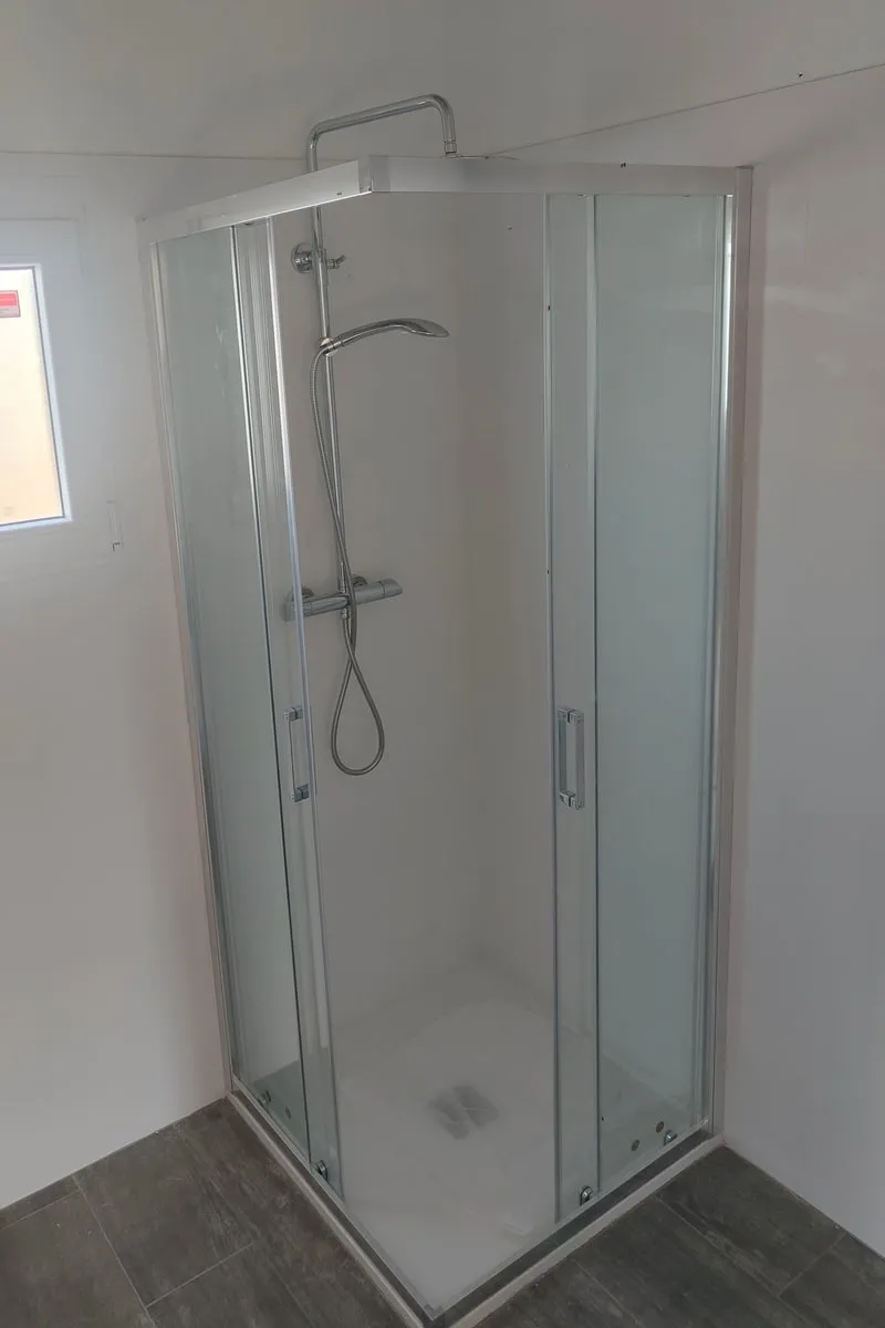 Ducha de esquina con mampara de cristal y columna de ducha termostática