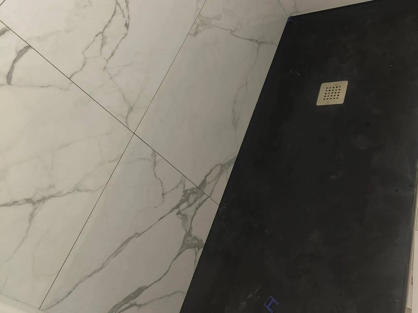 Ducha con plato negro y paredes alicatadas con piezas grandes efecto mármol